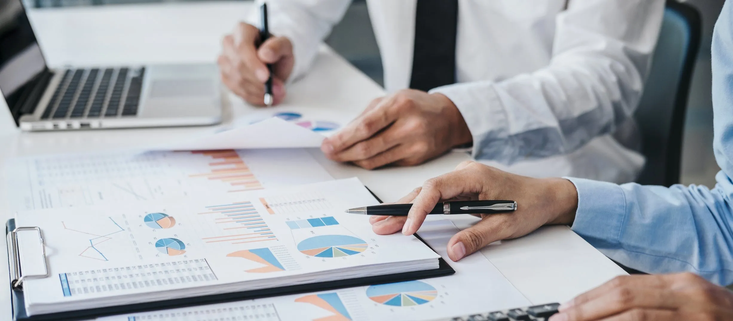 Two men analyzing and working on graphs at a desk